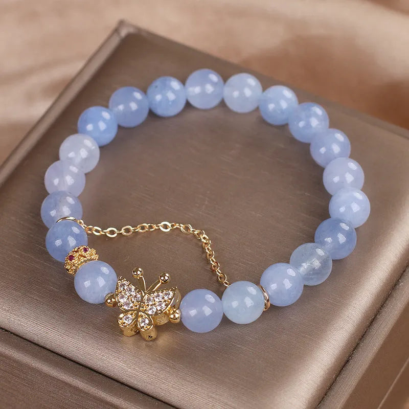 Sky blue crystal butterfly stretch bracelet for women with pearl and rhinestone accents on a plain background