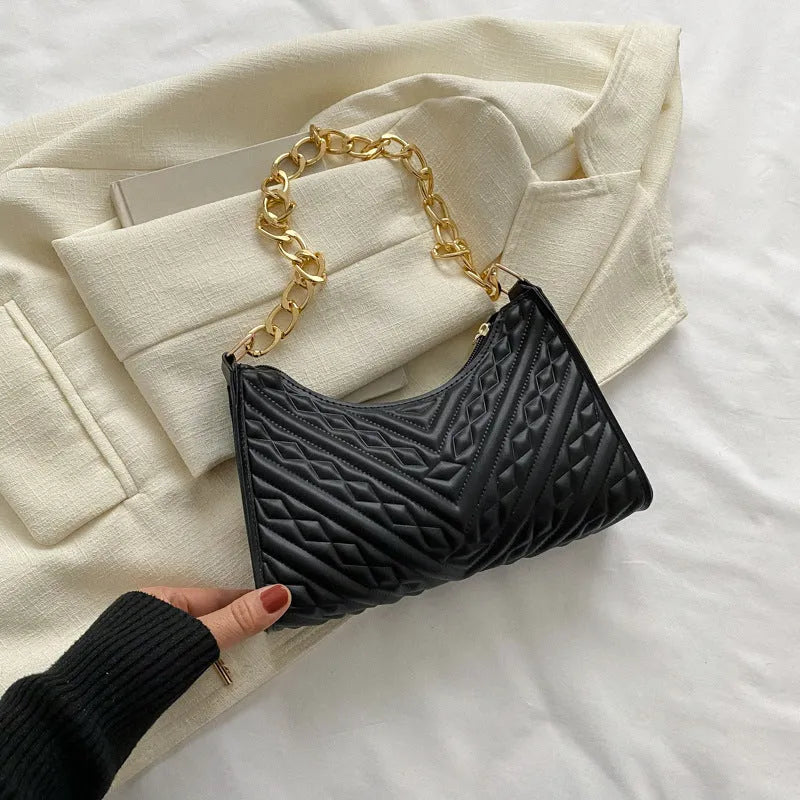 Black pleated chain baguette shoulder bag with adjustable strap and soft handle on white background
