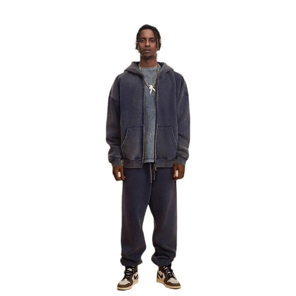 Man wearing a vintage washed dark green hooded cardigan with a double zipper and fleece lining.