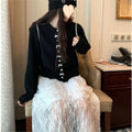 Women's light blue cardigan sweater with a black bow and pearl buttons, open over a white top.