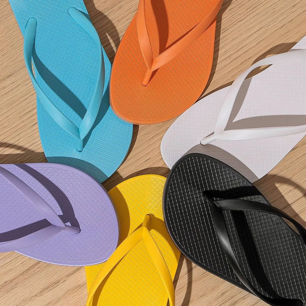 Foldable orange, purple, black, and white plastic beach slippers with non-slip PVC soles.