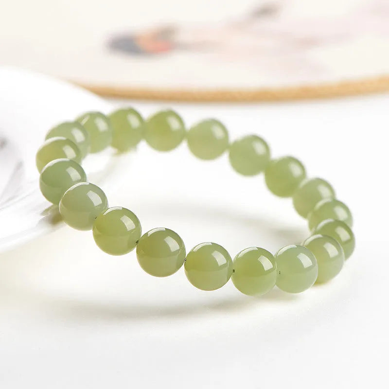 Polished Hetian jade ball bracelet in ice-like clear water colour on a wrist, showing bead detail.