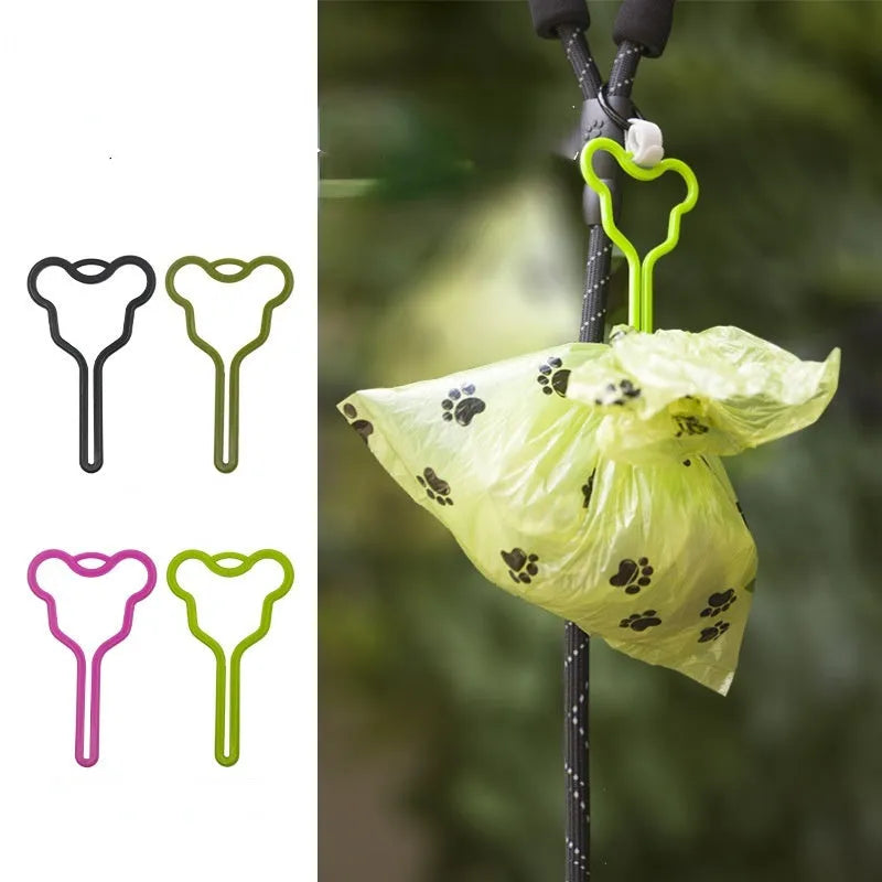 A hands-free dog poop bag holder with a fixed clip and adjustable hook and loop fastener attached to a dog leash.