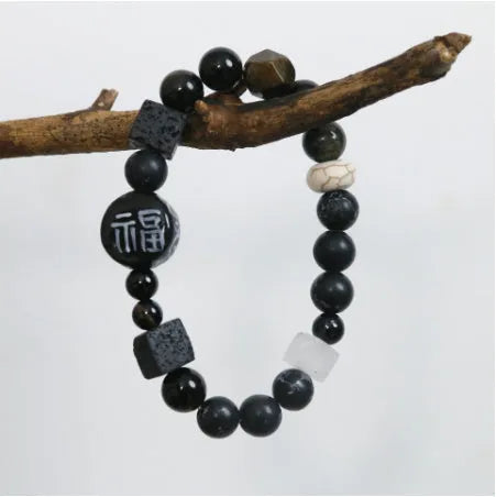 Hand-woven natural glitter stone black agate ceramic bracelet with round geometric beads on a neutral background