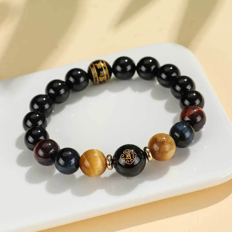 Black agate beaded bracelet with gold tiger eye accent and Chinese zodiac bodhisattva charm on neutral background
