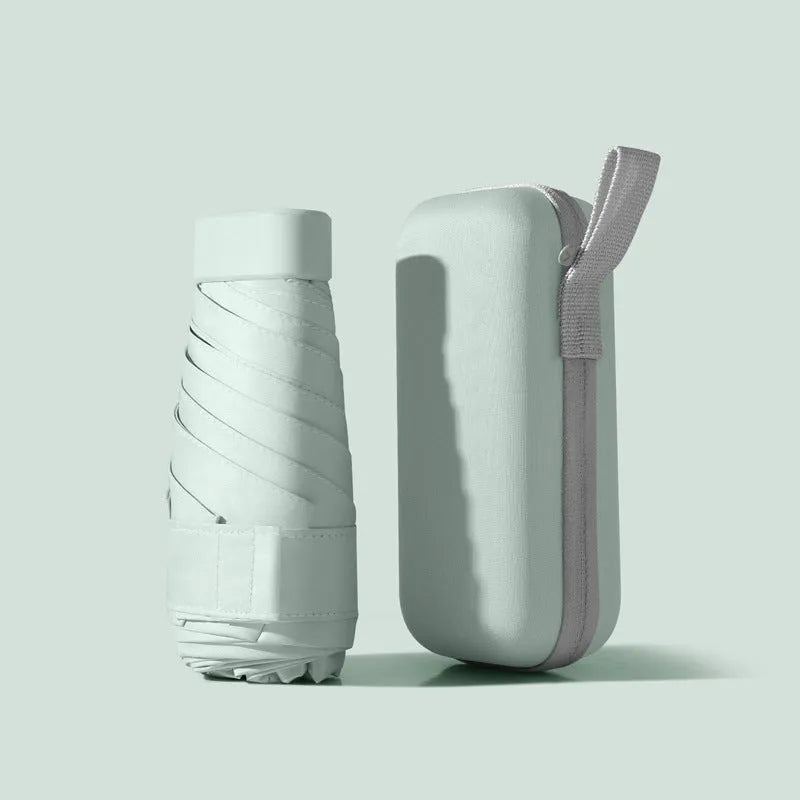 Compact six-fold umbrella in mint green with a capsule box, showing its folded size and rubber handle.