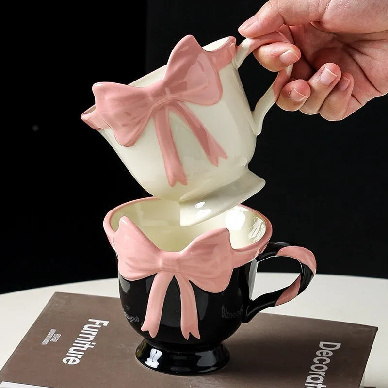 White ceramic mug with a pink heart and black bow design, 350ml capacity.