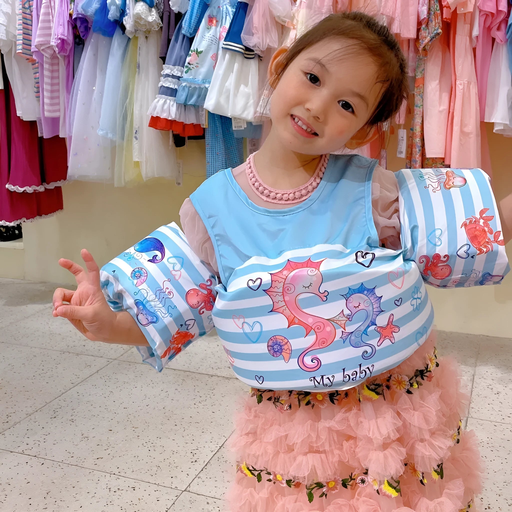 Child wearing a cartoon-themed swimsuit with integrated arm swimming rings for water safety.