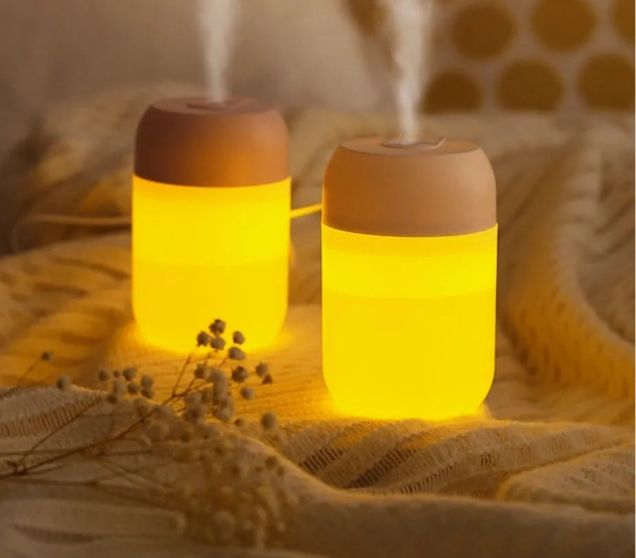 White cylindrical USB mini humidifier with charging cable on desk