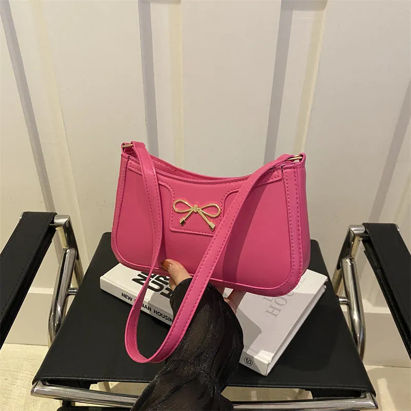PU leather baguette bag with bow decoration in rose red colour, 24x14x5 cm size on white background