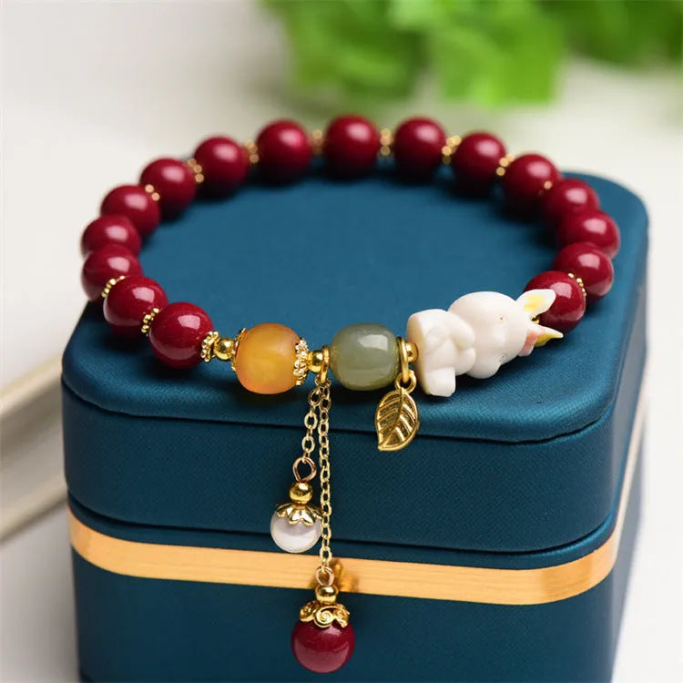 Women's bracelet with natural beeswax, purple gold sand beads, and a red cinnabar rabbit charm.