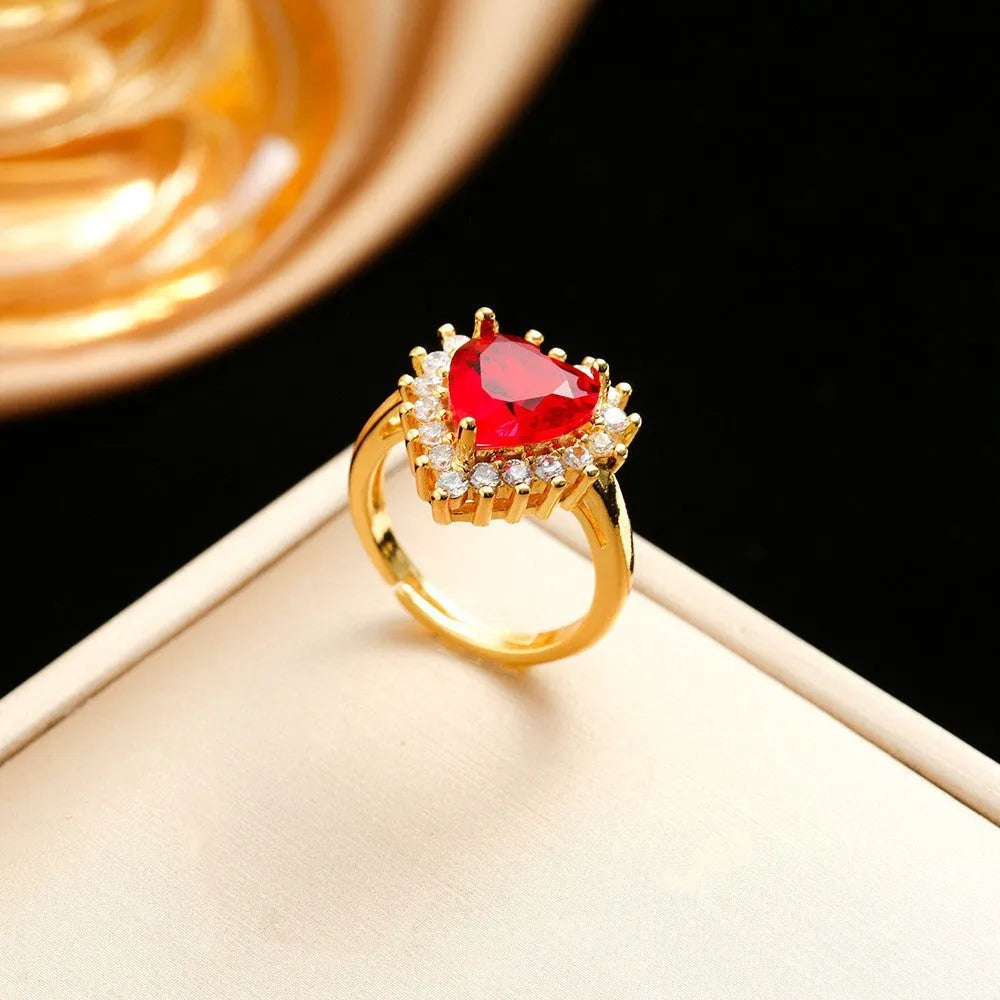Gold red titanium steel jewellery set with heart and flower pendant, stud earrings, and ring on a water wave chain.