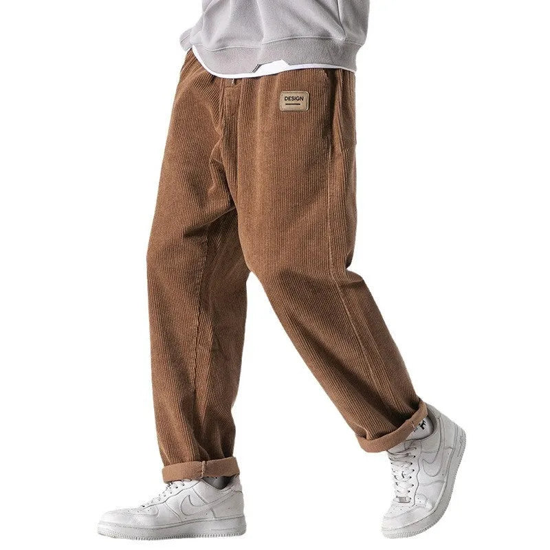 Men's loose straight corduroy sports trousers in black, front view, lying flat, showing waist and leg cut