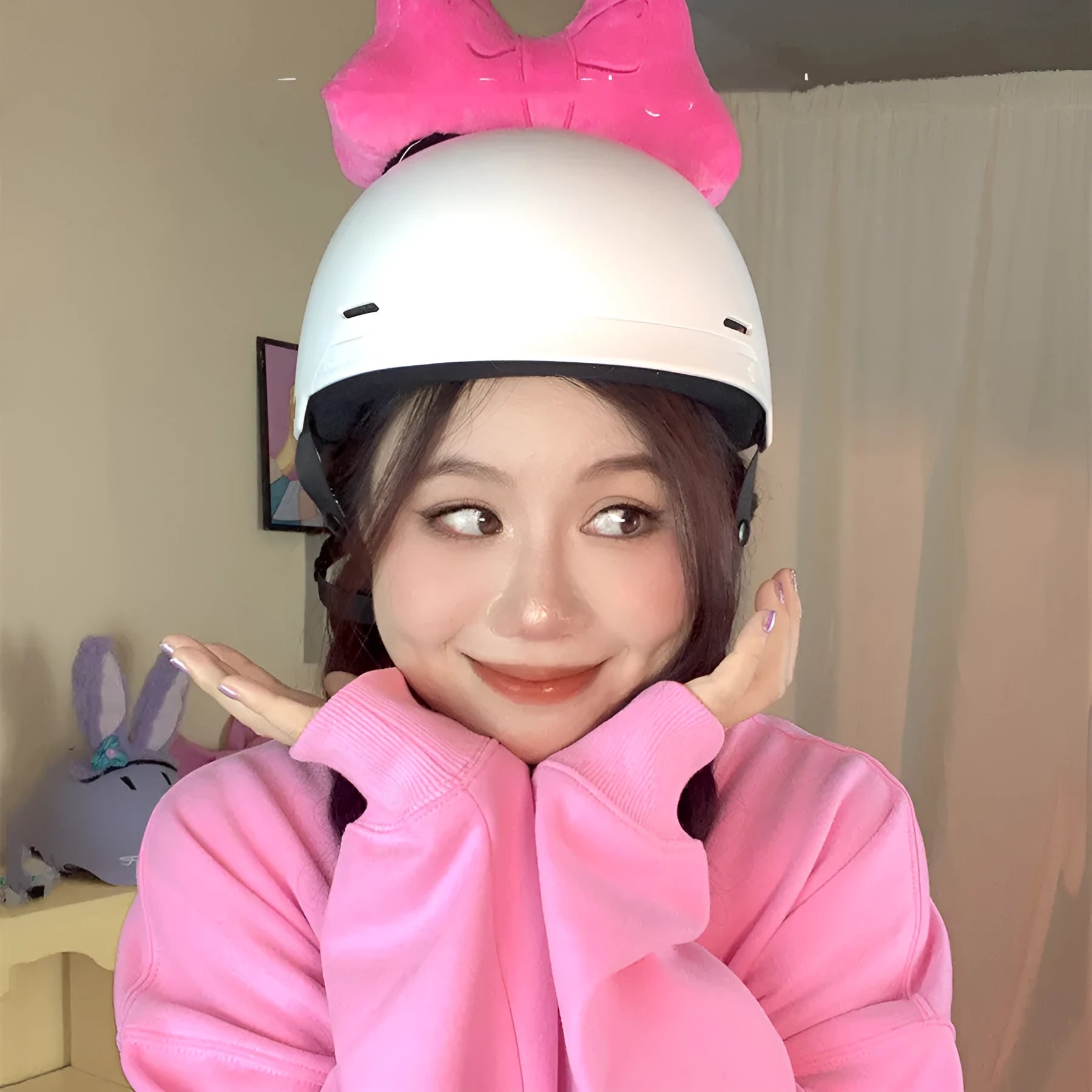 Plush bow tie helmet decoration in red, peach pink, and rose pink colours shown on a motorcycle helmet.