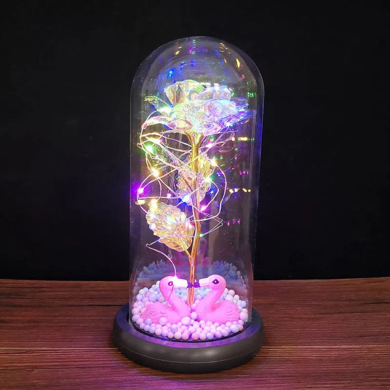 Gold artificial rose inside glass dome with LED lights on black base for home display