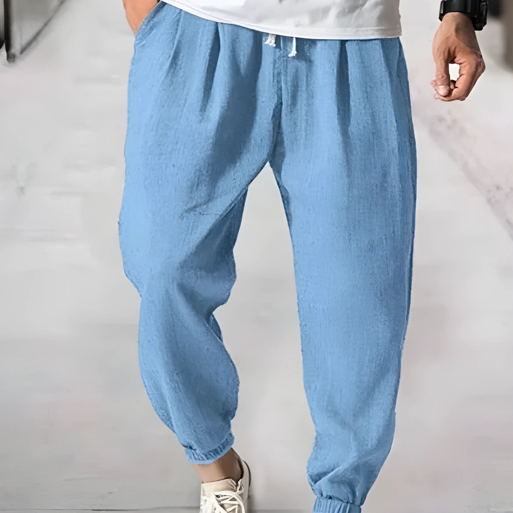 Men's loose cotton ankle banded trousers in khaki colour on a hanger.