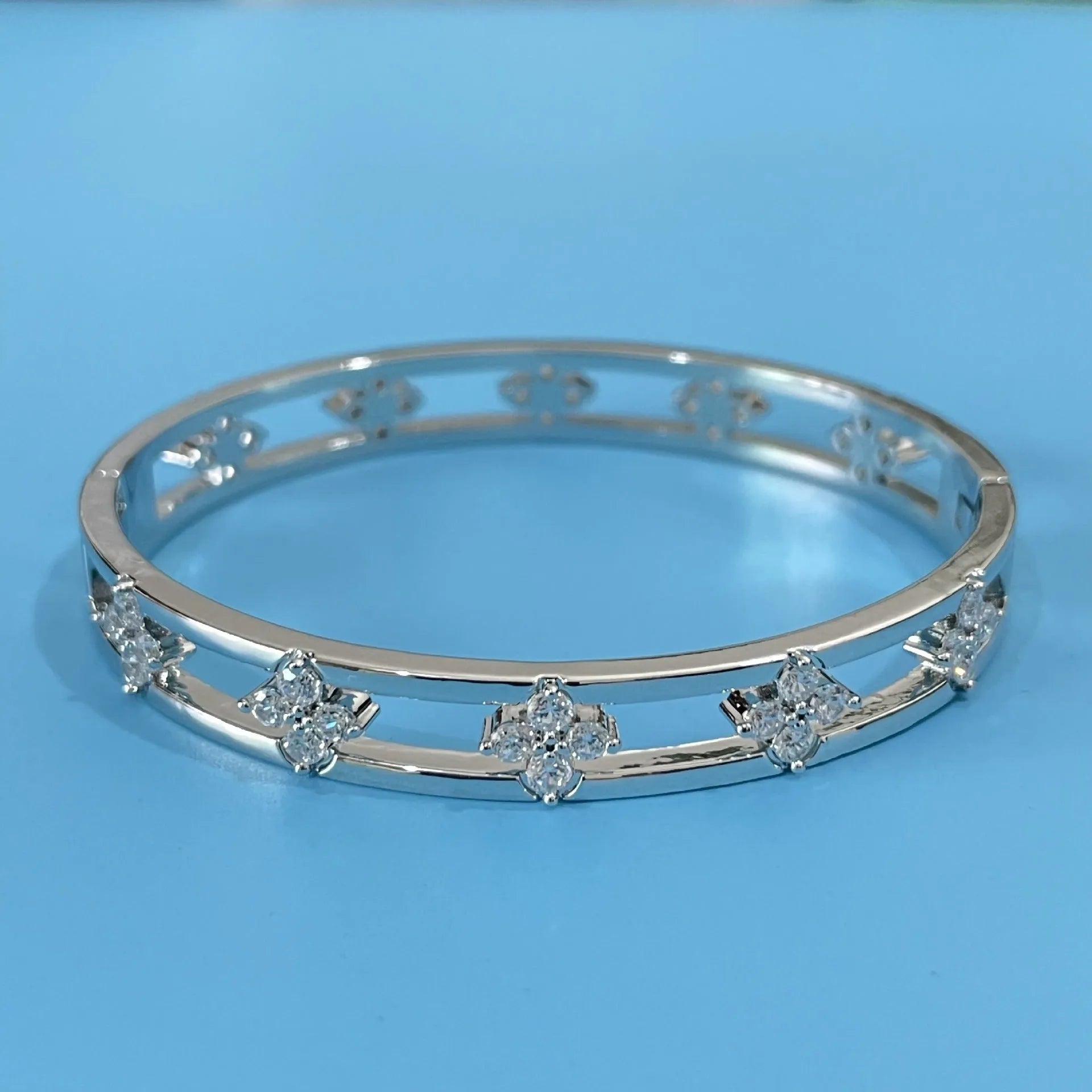Gold and silver women's hollow bracelet with zircon inlay and a four-leaf clover design.