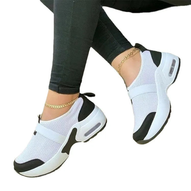 Women's white mesh flat sneakers with round toe and rubber sole on a light background.