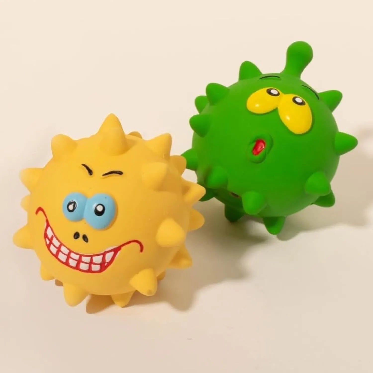 Set of four coloured natural latex squeaky dog balls with cute faces and textured surfaces
