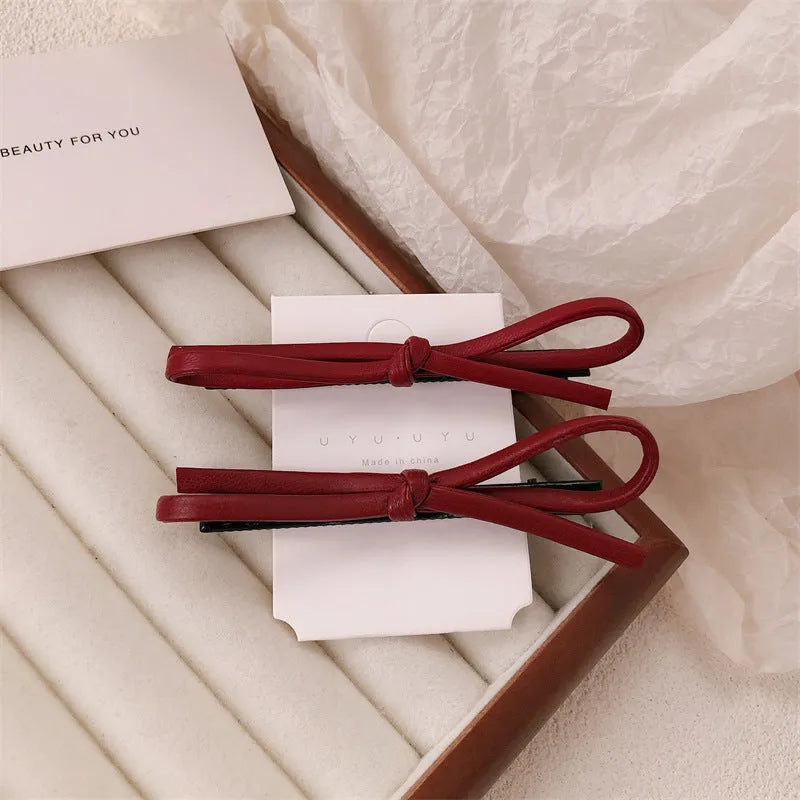 Wine red leather bow hair barrettes for women, showing front and side views