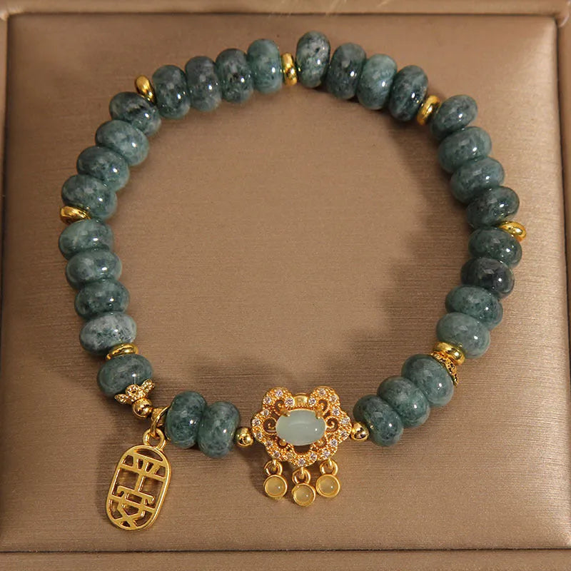Close-up of a women's bracelet with green emerald jade abacus beads and a metallic alloy safety lock clasp.
