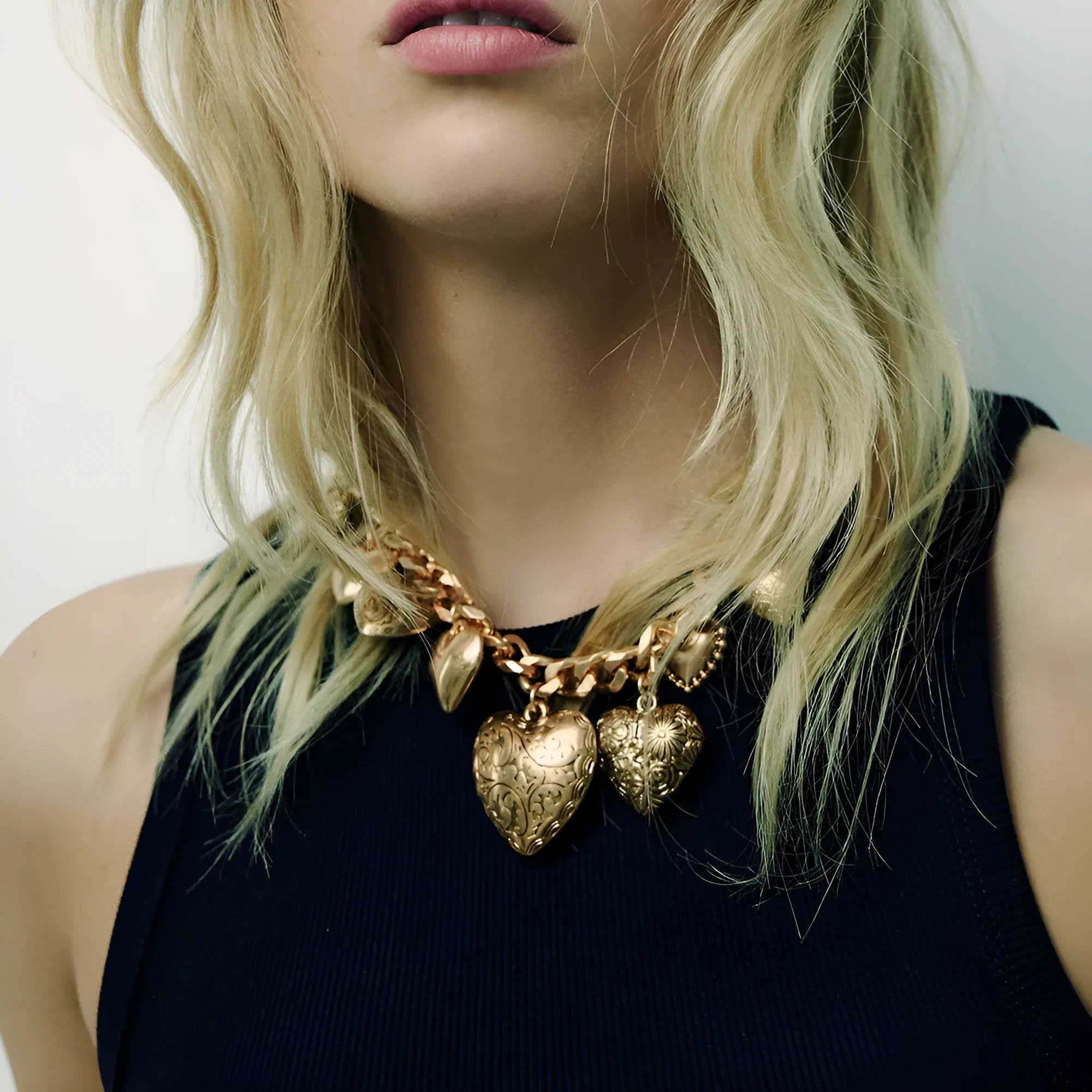 Carved heart-shaped pendant necklace on an adjustable metal chain in gold colour.