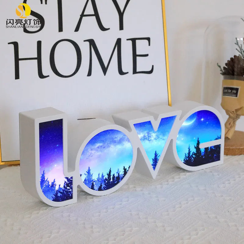 LED LOVE light with rainbow lampshade on a table against a dark background