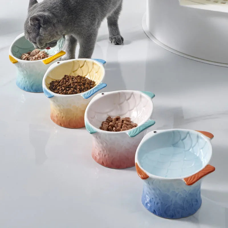 Blue ceramic fish-shaped cat feeder bowl with a tilted, elevated design on a non-slip base.