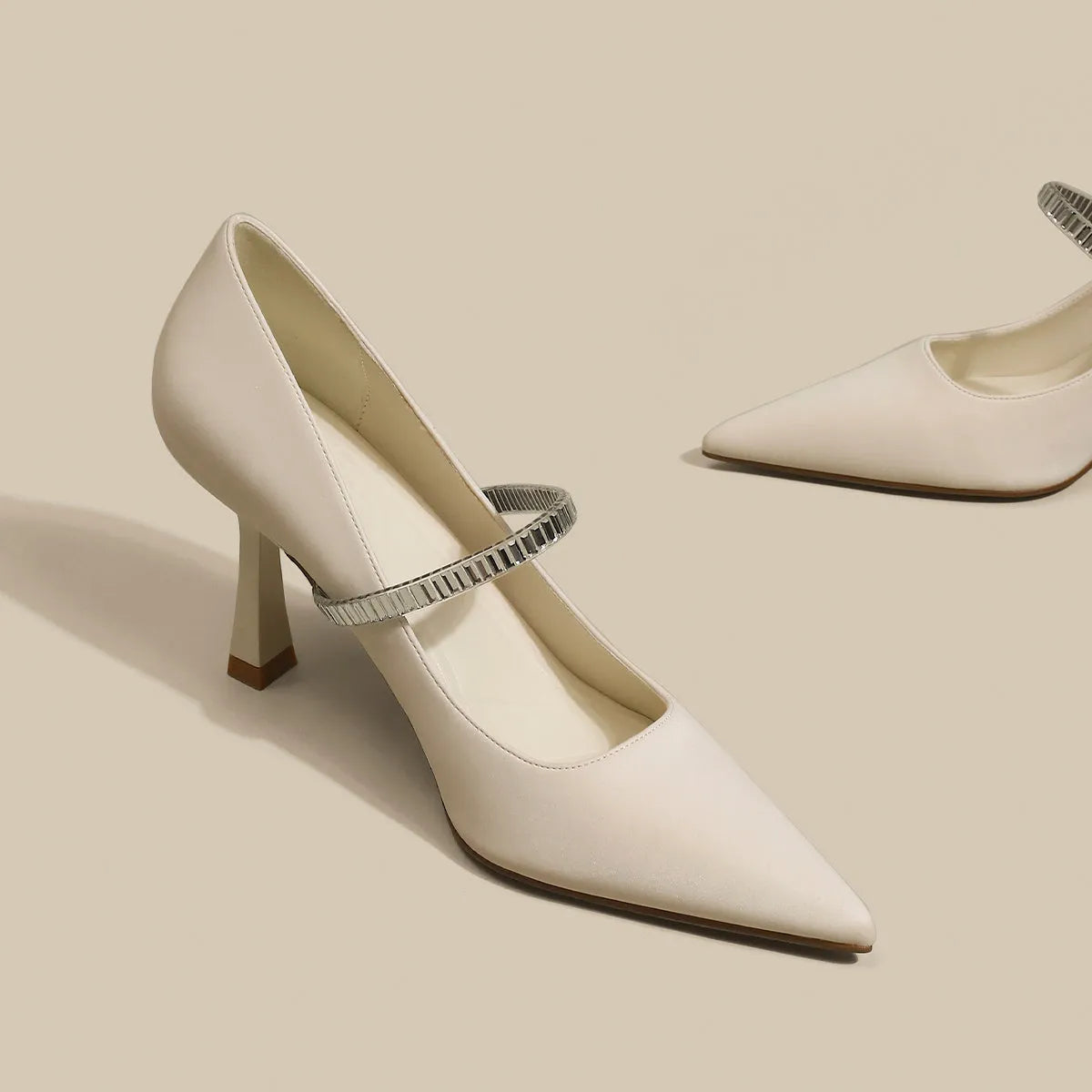 Women's black stiletto heel sandals with pointed closed toe, buckle strap, and skirt detail on a white background