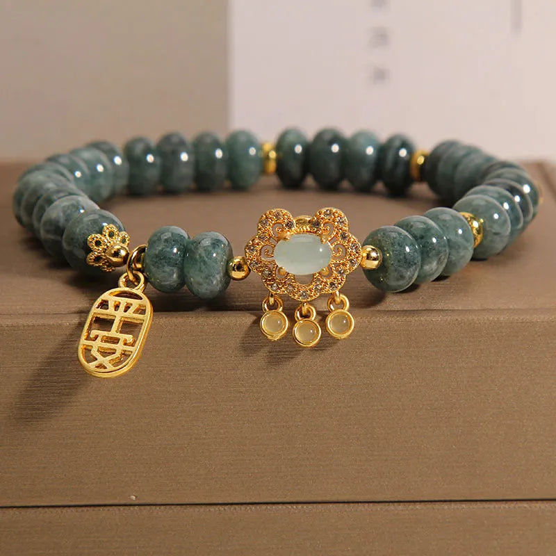 Close-up of a women's bracelet with green emerald jade abacus beads and a metallic alloy safety lock clasp.