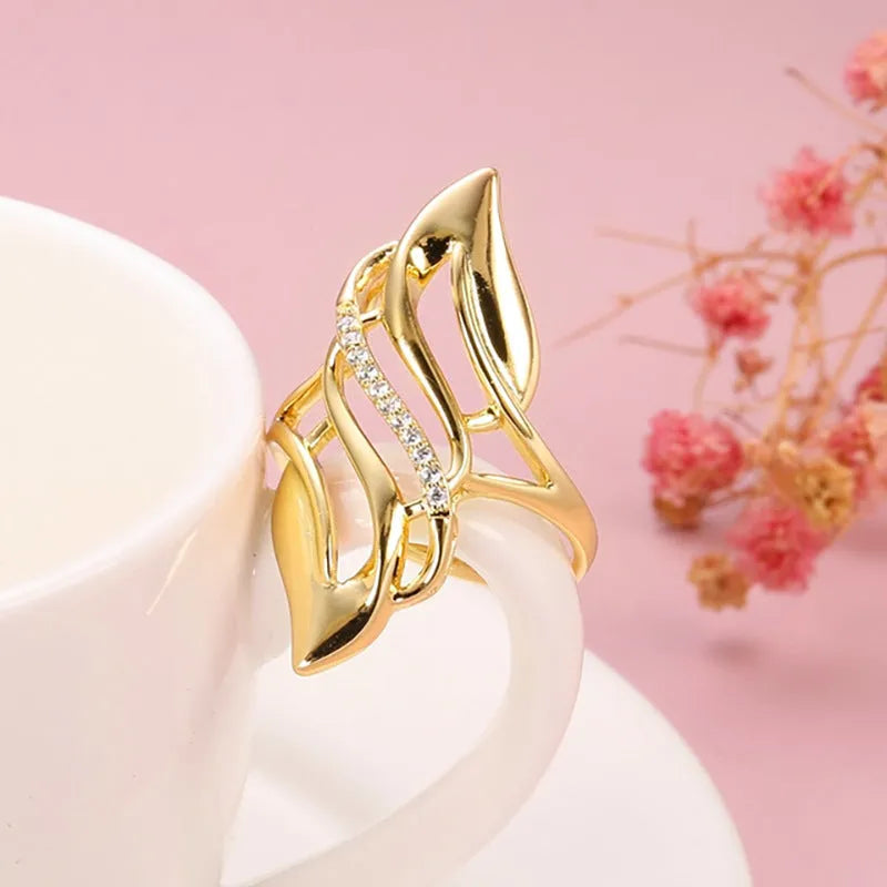 Gold tone exaggerated curve copper ring with zircon stone on white background