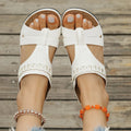 Pair of beige Roman style slippers with a fish mouth toe and slope heel on a rubber sole.