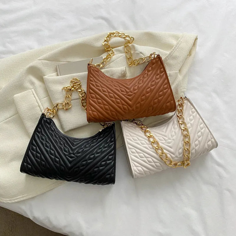 Black pleated chain baguette shoulder bag with adjustable strap and soft handle on white background
