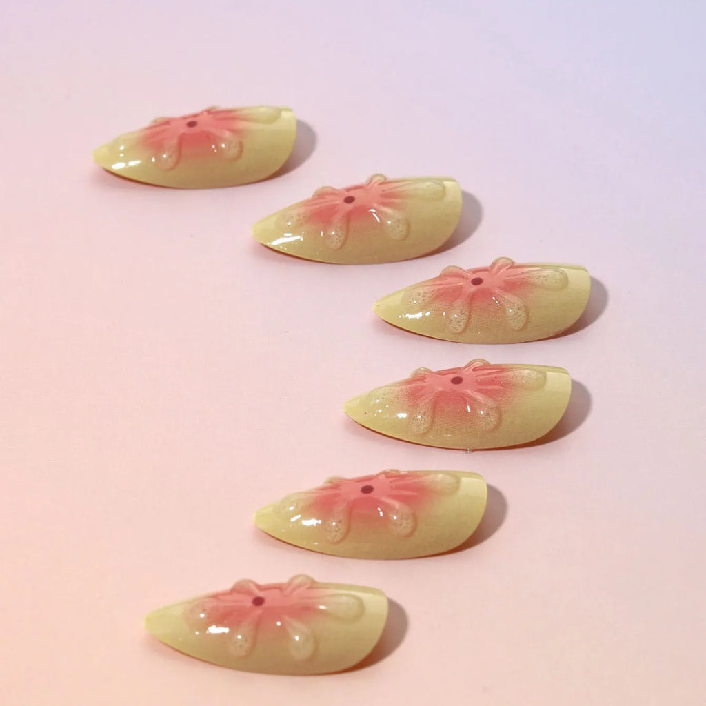Detachable fake nails with pink 3D cartoon flowers, jelly glue, and filing strip on white background