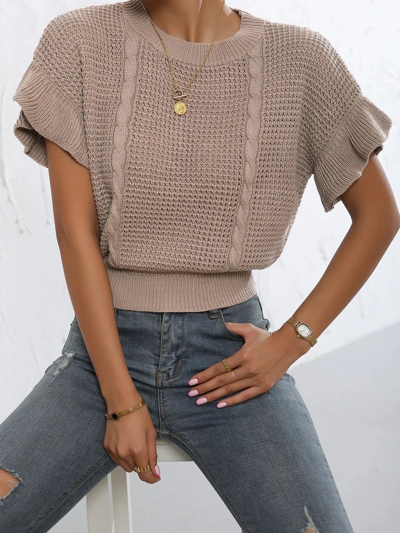 Loose fit knitted pullover with round neck and textured ruffled short sleeves in a neutral colour.