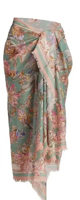 Creamy-white floral print women's three-piece bikini set with top, briefs, and skirt on a beach background.
