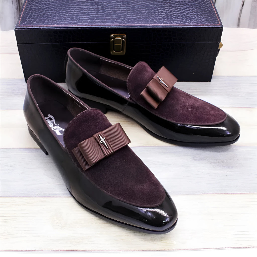 Men's black patent leather dress shoes with a gold tassel detail on the front.