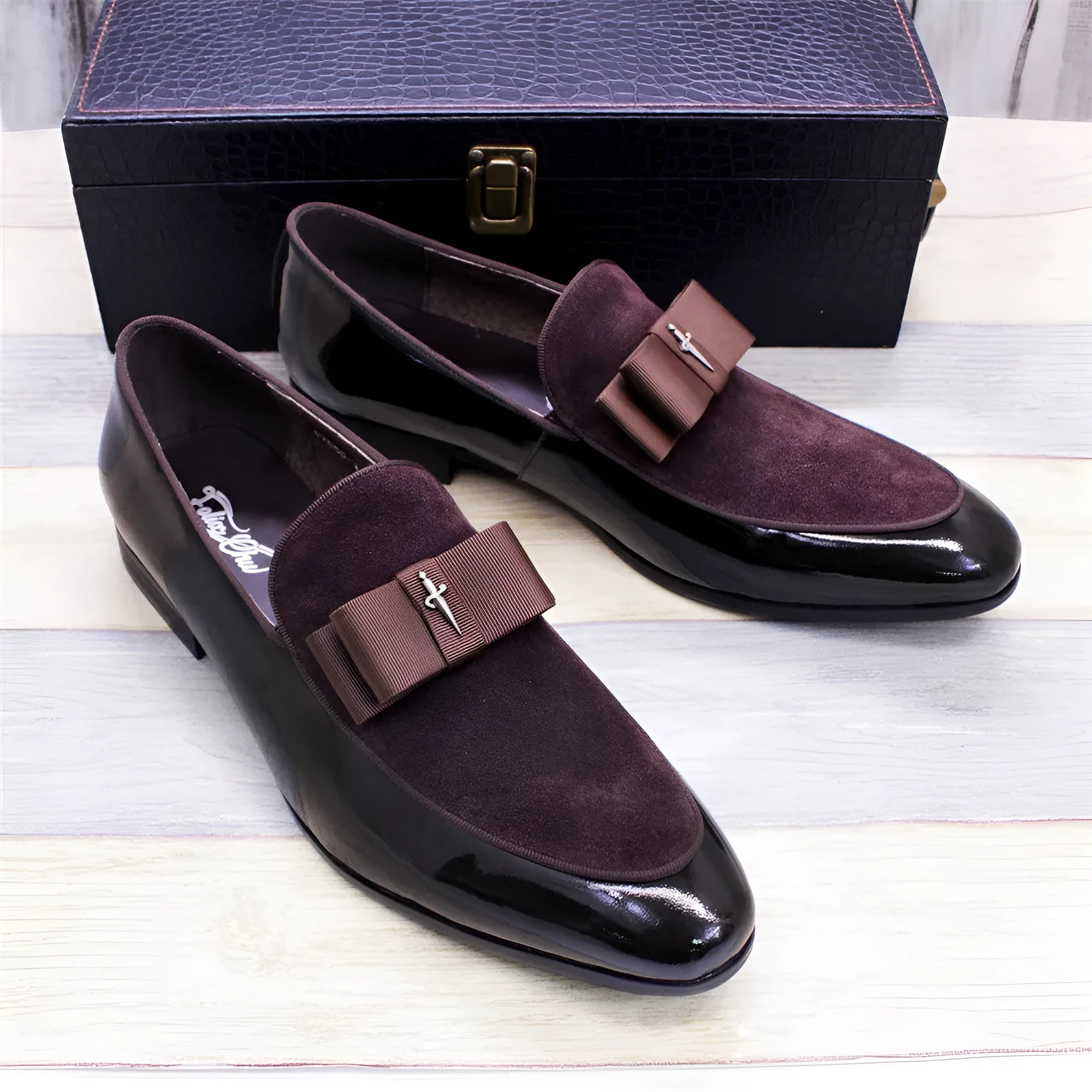 Men's black patent leather dress shoes with a gold tassel detail on the front.
