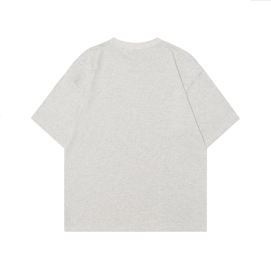 Adult male model wearing a grey loose-fit t-shirt with a retro character design print on the front.