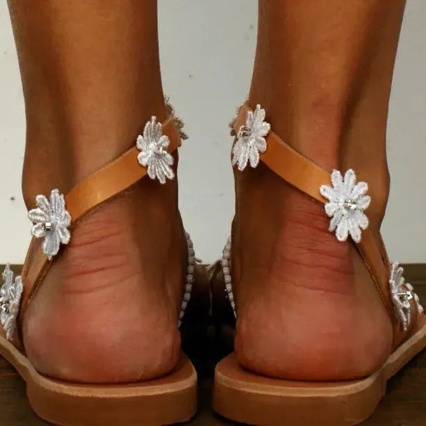 Brown ladies Roman sandals with floral decoration on PU upper and flat rubber sole