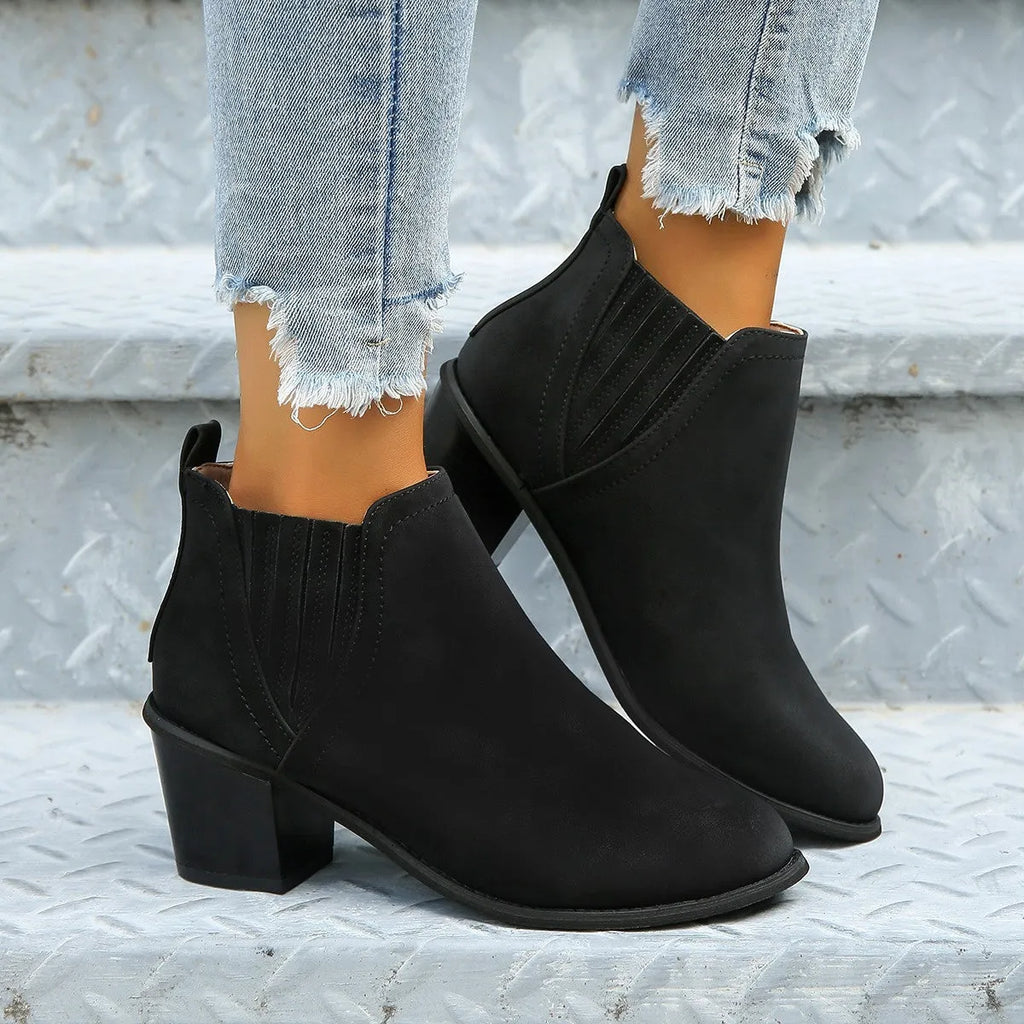 Black women's pointed toe ankle boots with a thick square low heel and slip-on design.