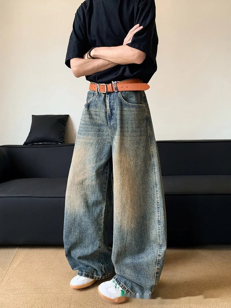 Man wearing retro blue distressed denim wide-leg trousers with a slim fit and zipper fly