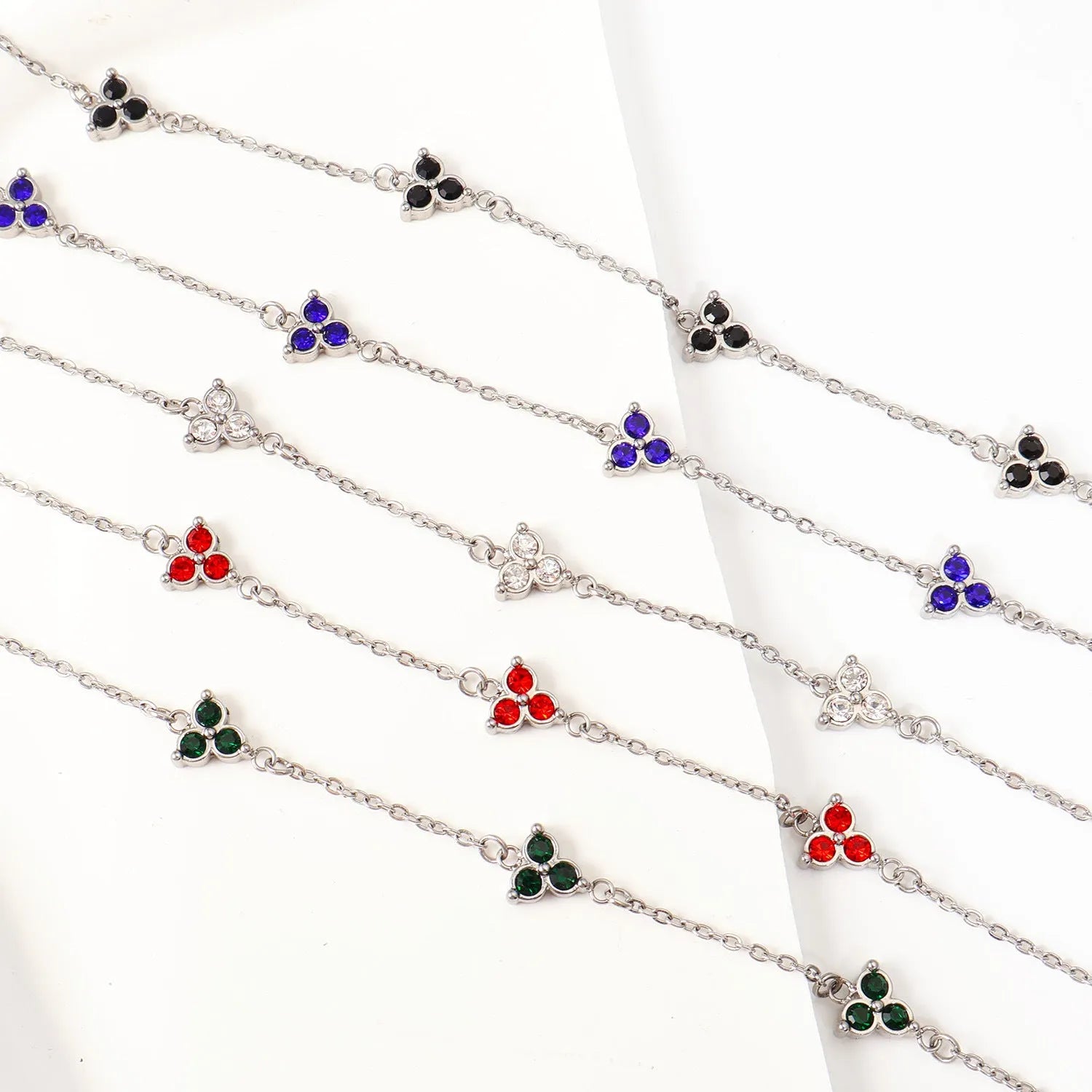 Geometric stainless steel women's bracelet with three diamond shapes and coloured stone settings.