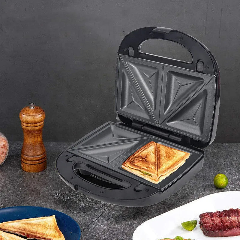 Black double-sided electric sandwich pan with brushed stainless steel cover on a kitchen counter.