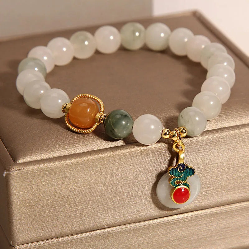 Women's ice jade bracelet with pearl accents and a Xiangyun jade buckle on a wrist.