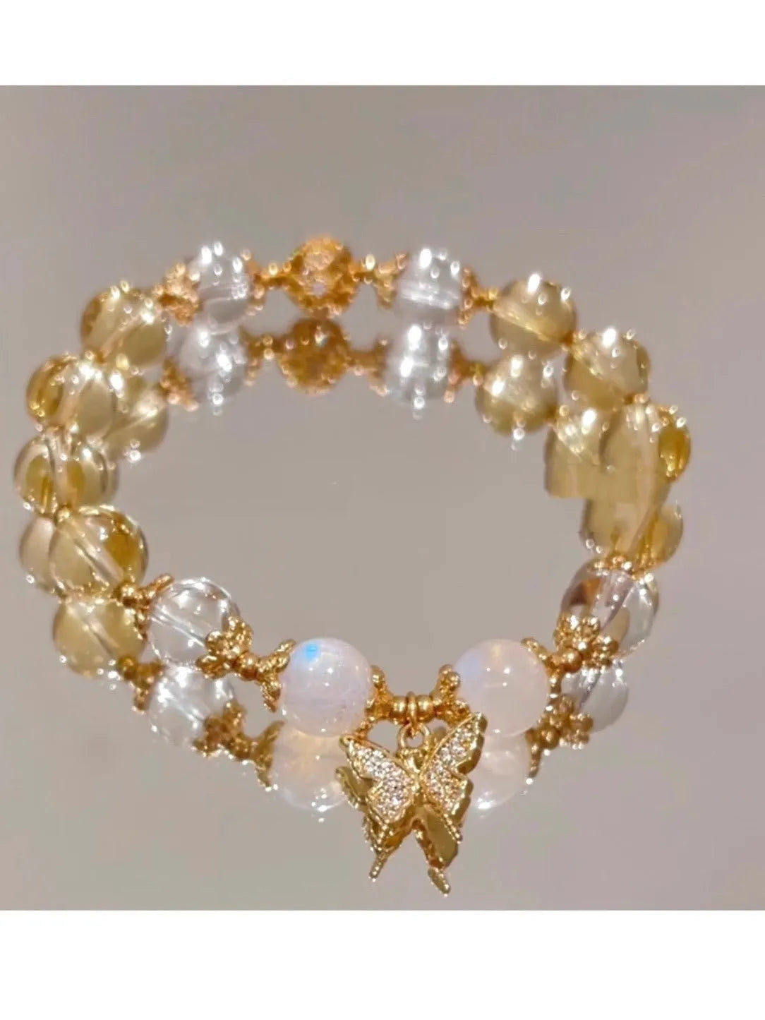 Moonstone white crystal beaded bracelet with citrine butterfly pendant on a white background