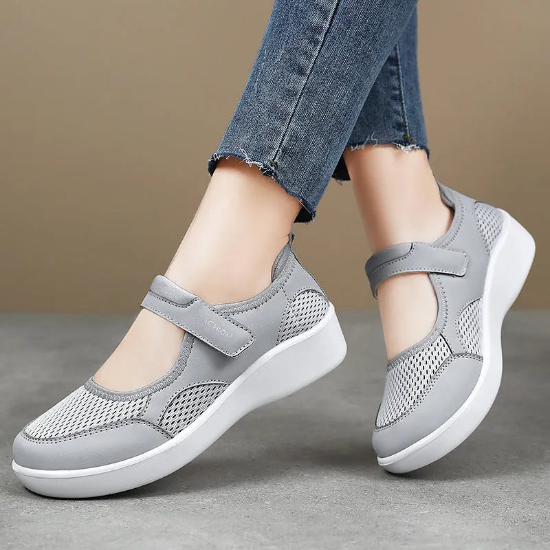 Women's grey low-top cloth shoes with mesh upper and Velcro strap on a flat sole.