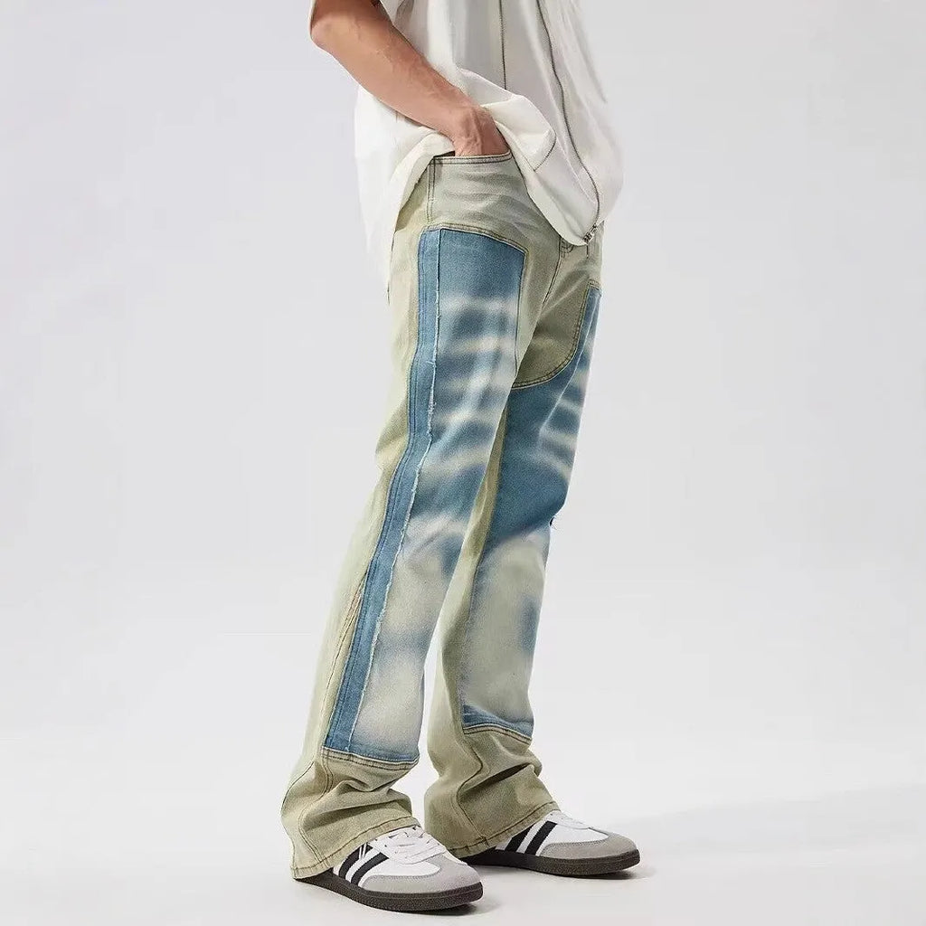 Yellow and blue retro patchwork jeans with a splash-ink damaged design, shown on a mannequin.