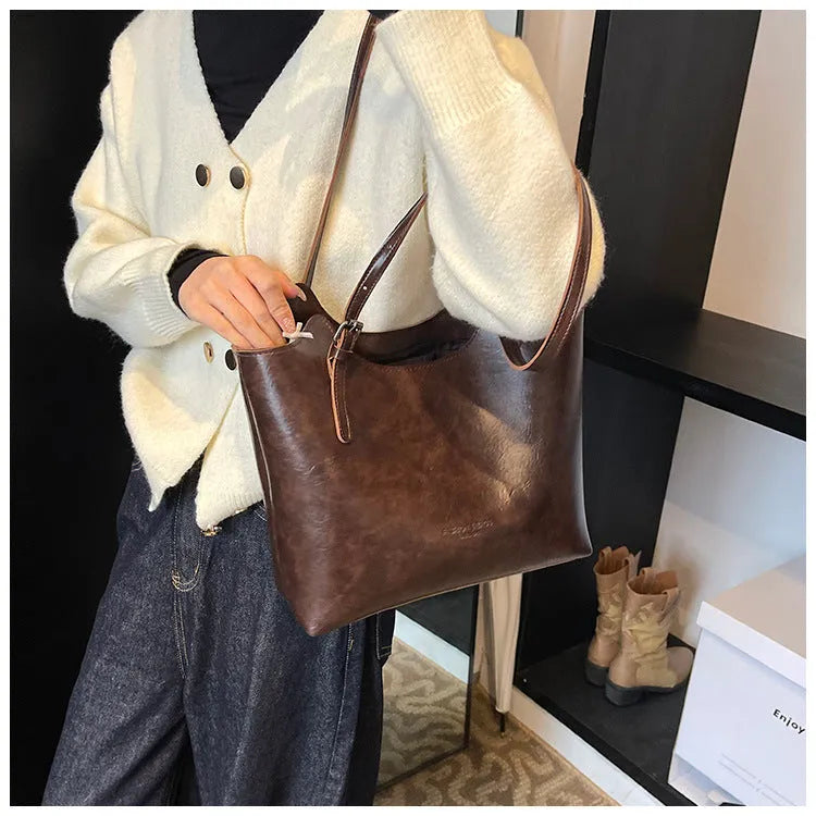 Women's PU commuter shoulder bag in black with stitching details and optional ribbon pendant, horizontal square shape