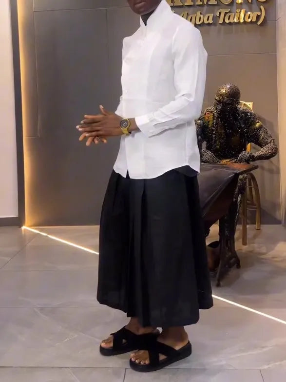 White asymmetric long sleeve shirt with black pleated pants set on a model for casual wear
